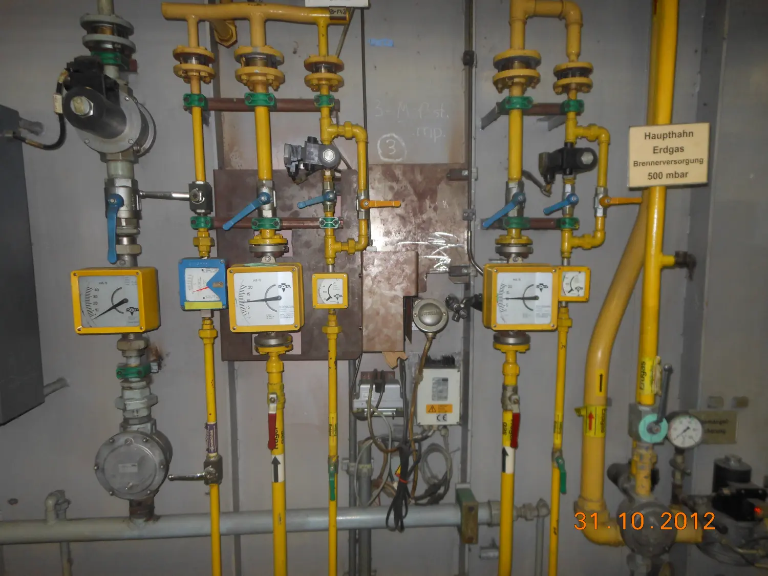 Ein komplexes System aus gelben Rohren und Messgeräten, die Bestandteile einer Erdgaspipeline oder einer Gasregelanlage sind. von Härterei Service Dirk Gieselmann